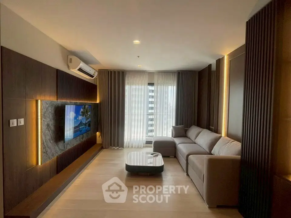 Modern living room with sleek design and large TV, featuring a cozy sofa and stylish lighting.