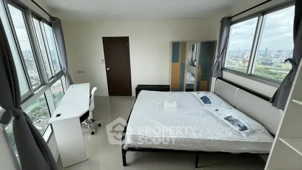 Spacious bedroom with panoramic city views and modern furnishings.