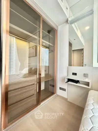 Modern bedroom with glass wardrobe and sleek design in a contemporary apartment.