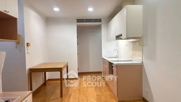 Modern kitchen with wooden flooring and sleek cabinetry in a cozy apartment.