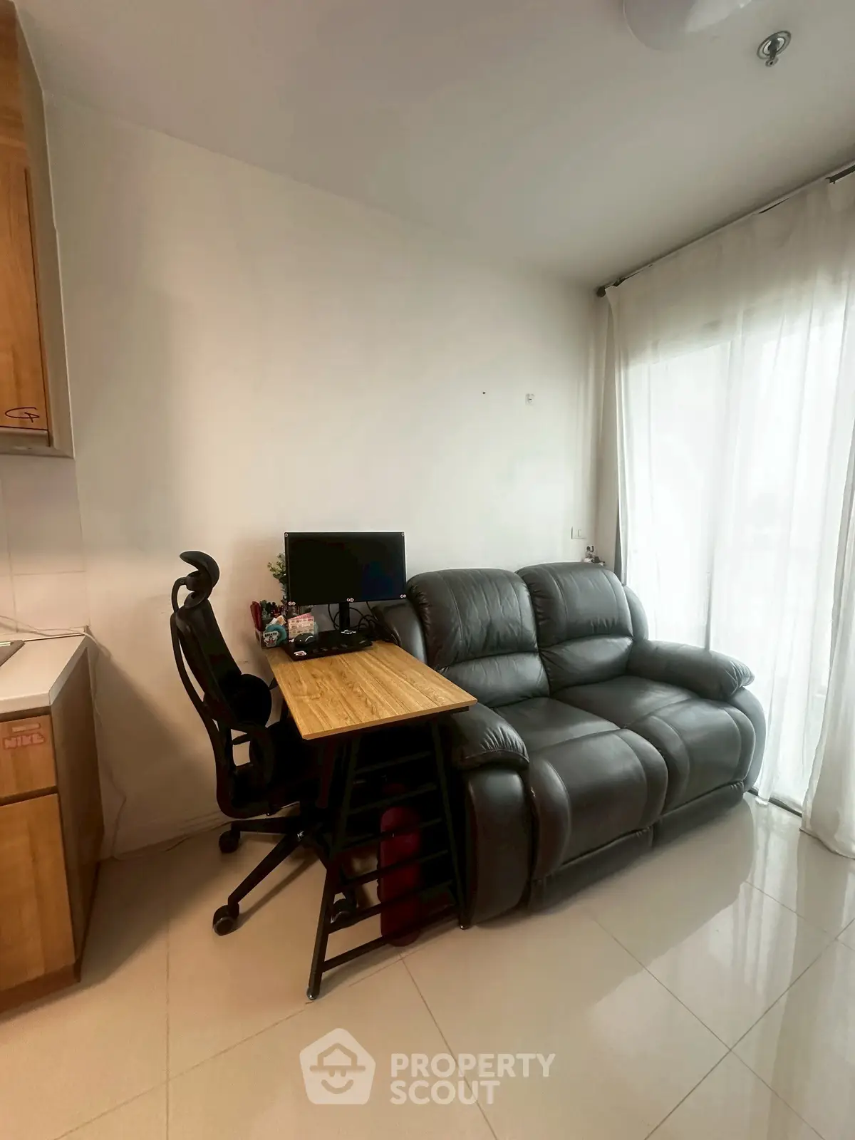 Cozy living room with leather sofa and modern workspace setup, perfect for urban living.