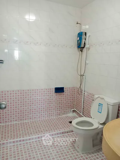 Spacious bathroom with modern shower and toilet in tiled interior