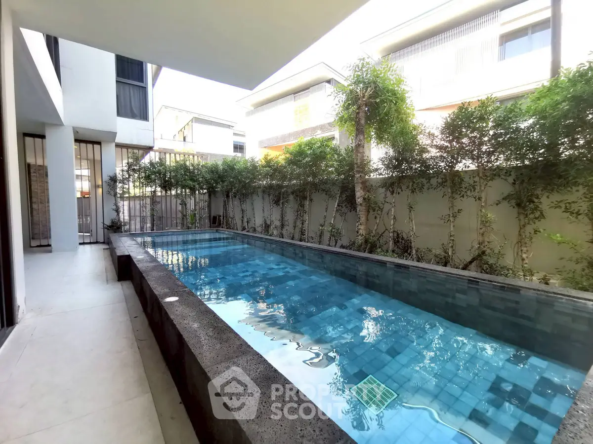 Luxurious modern poolside view with lush greenery and sleek architecture