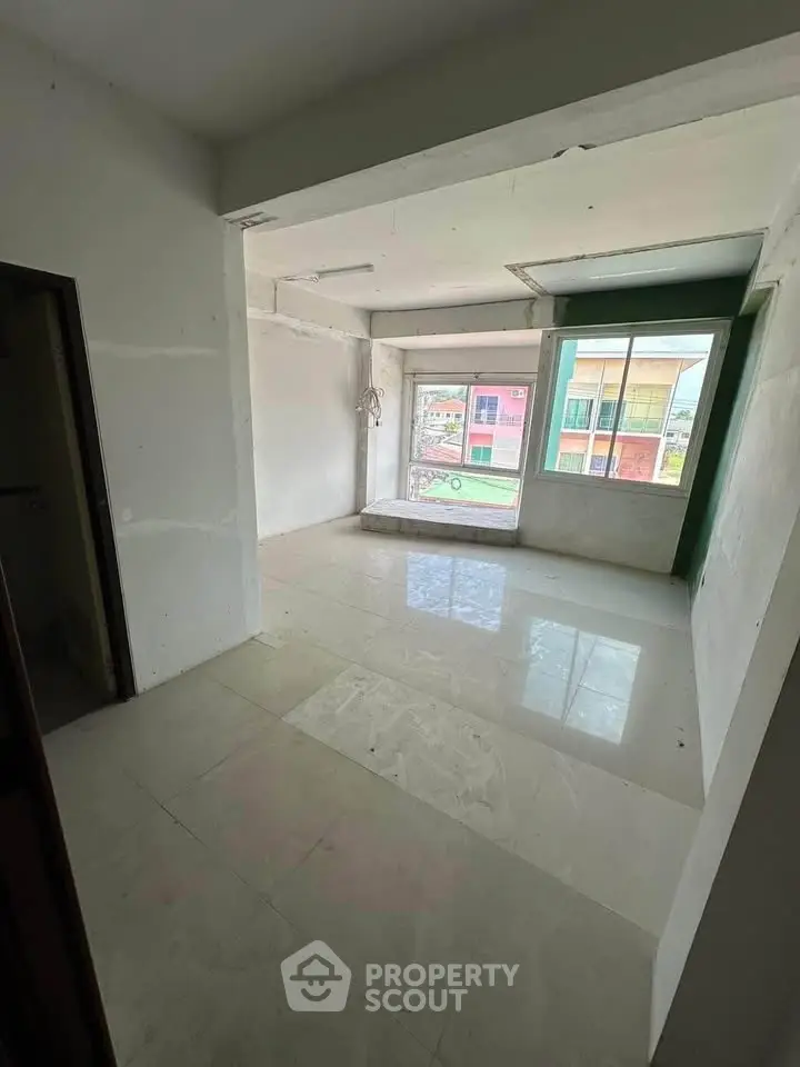 Spacious unfurnished room with large windows and glossy tiled floor, ideal for customization.