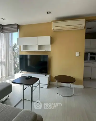 Modern living room with sleek furniture and large TV, featuring an open layout and natural light.