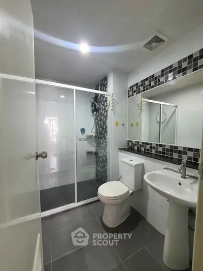 Modern bathroom with glass shower, sleek fixtures, and stylish tile accents.