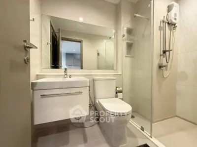 Modern bathroom with sleek fixtures and glass shower enclosure in a contemporary apartment.