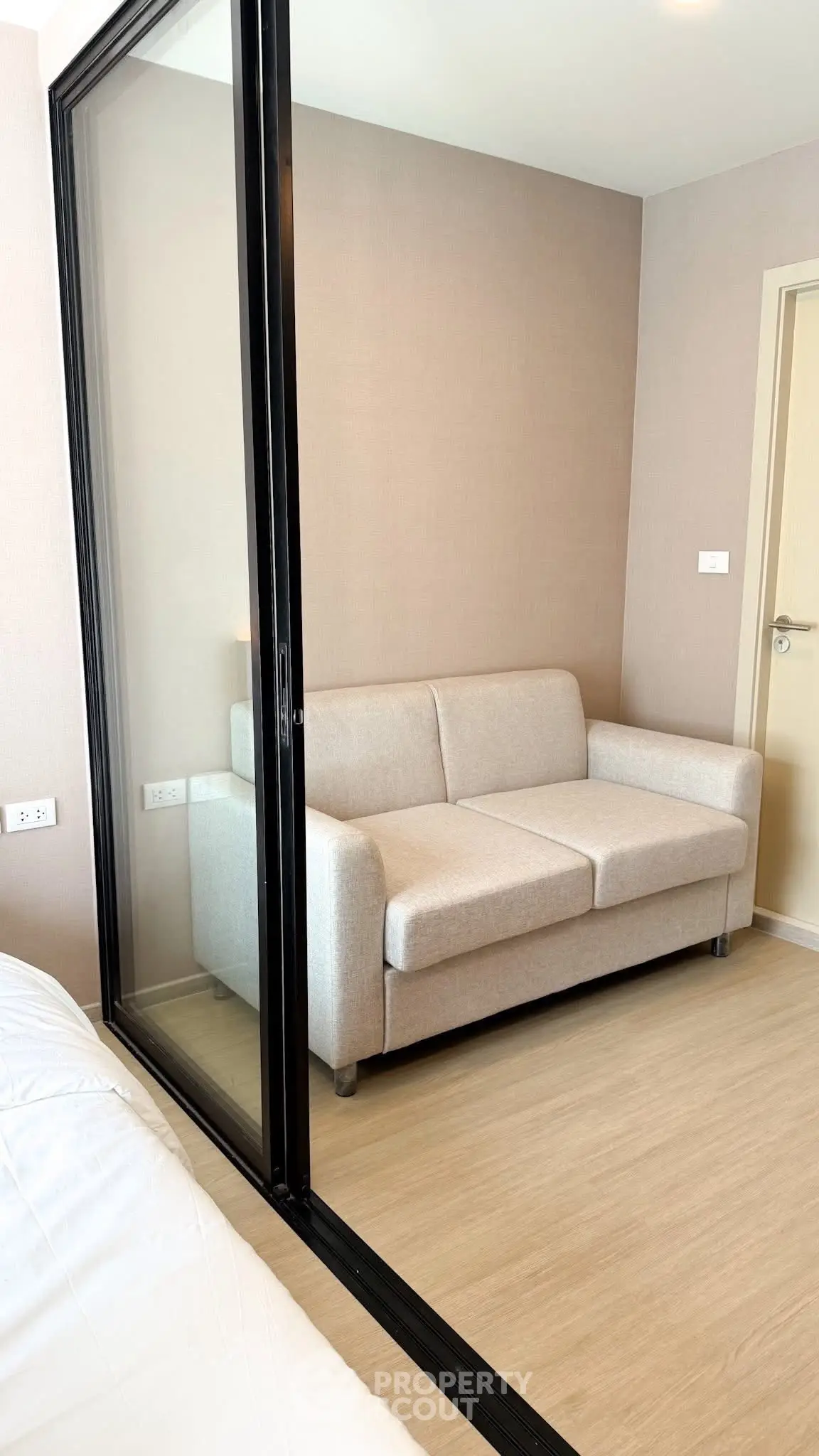 Modern apartment with cozy living area featuring a stylish sofa and sleek glass partition.