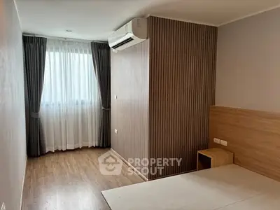 Modern bedroom with wooden flooring and air conditioning