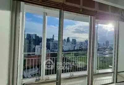 Stunning cityscape view from high-rise apartment balcony with large windows.