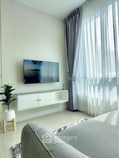 Modern living room with large window, sleek TV setup, and elegant decor.