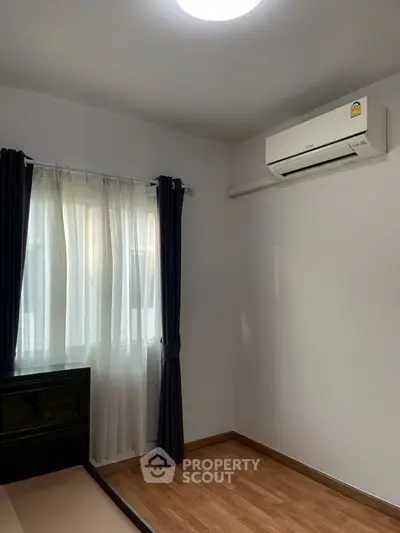 Cozy bedroom with wooden flooring and air conditioning unit