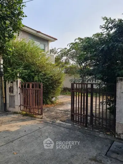 Charming gated entrance to a serene residential property with lush greenery.