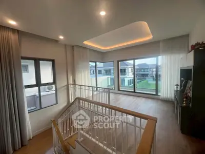 Spacious modern living room with large windows and elegant staircase, offering a bright and airy ambiance.