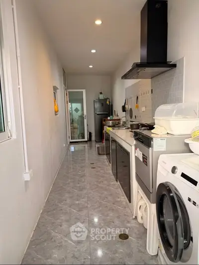 Modern kitchen with sleek appliances and open layout, featuring a washing machine and stylish backsplash.