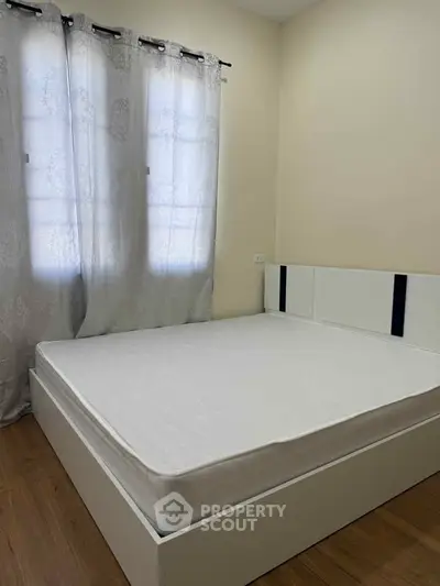 Cozy bedroom with natural light and modern decor, featuring a comfortable bed and elegant curtains.