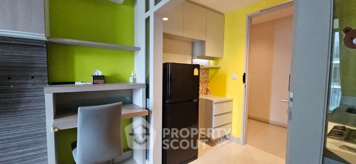 Modern kitchen with vibrant yellow walls and sleek black fridge in a compact apartment.