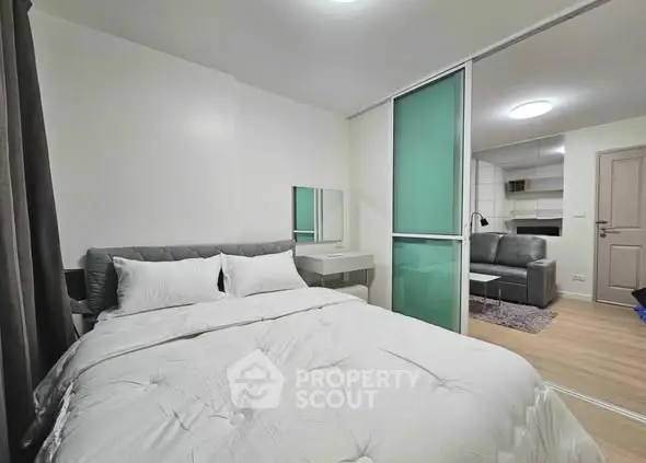 Modern bedroom with sliding glass door to cozy living area, stylish decor.