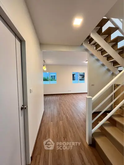Spacious modern interior with wooden flooring and staircase, ideal for family living.