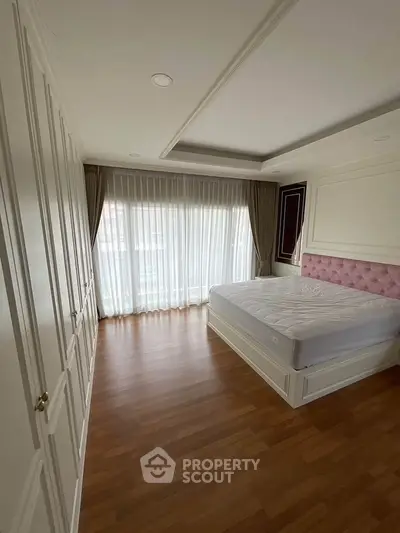 Spacious bedroom with elegant design and large window for natural light.