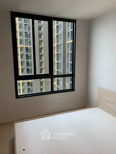 Modern bedroom with large window offering city view in high-rise apartment