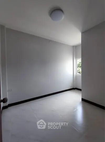 Spacious empty room with natural light and modern tile flooring