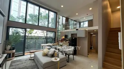 Luxurious modern living room with high ceilings and large windows offering natural light and garden view.