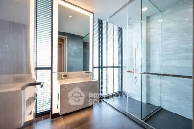 Luxurious modern bathroom with marble finishes and glass shower enclosure.