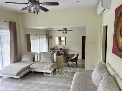 Spacious living room with modern furniture and dining area, featuring ceiling fans and natural light.