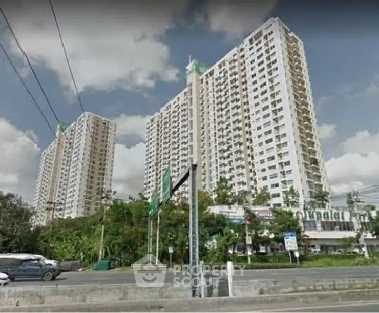 High-rise residential building with lush greenery and clear sky view.