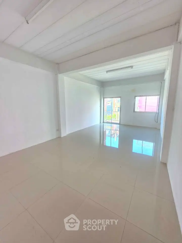 Spacious empty room with glossy tiled floor and bright natural light