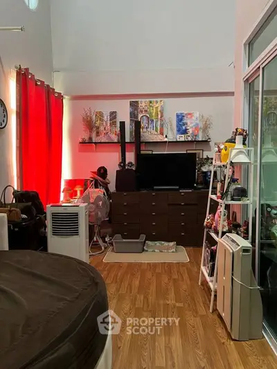 Charming living room with modern decor and vibrant red curtains, featuring a cozy atmosphere and stylish shelving.