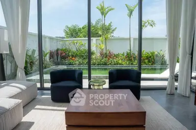 Luxurious living room with floor-to-ceiling windows overlooking a private garden and pool, featuring elegant furniture.