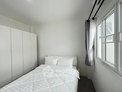 Cozy minimalist bedroom with white wardrobe and window view, perfect for relaxation.