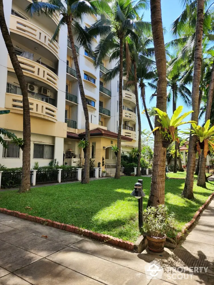 Charming residential building with lush garden and palm trees, perfect for serene living.