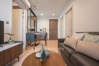 Modern living room with stylish decor and dining area, featuring cozy seating and elegant lighting.