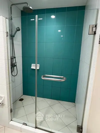 Modern bathroom shower with glass door and teal tiles