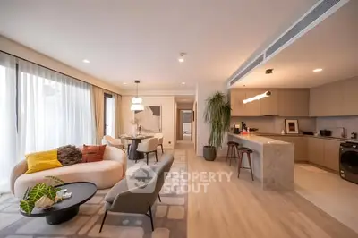 Spacious modern living room with open kitchen, stylish furniture, and natural light.
