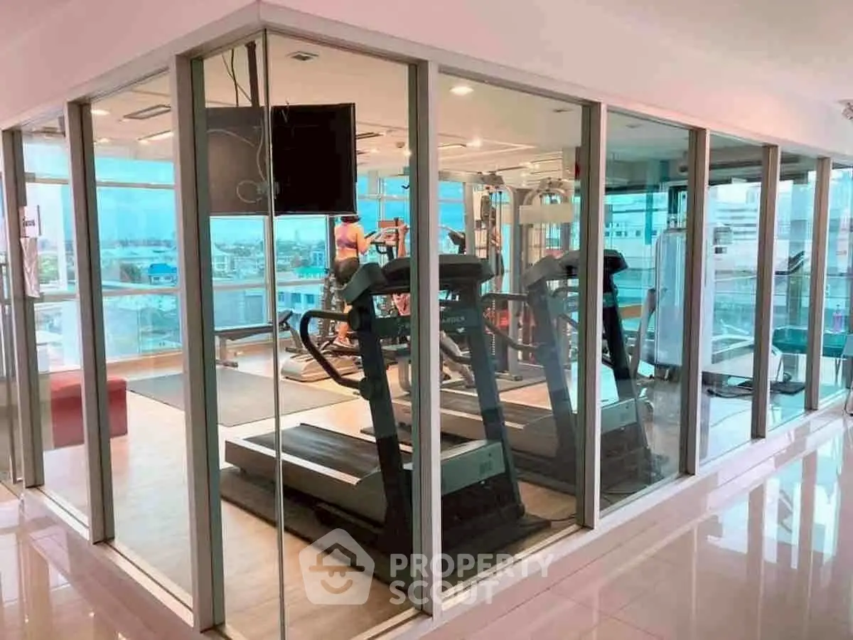 Modern gym with treadmills and city view in luxury apartment building.