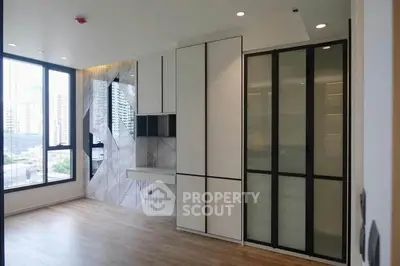 Modern apartment interior with sleek built-in storage and large windows offering city views.