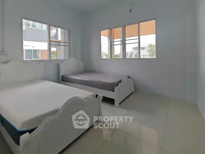 Spacious bedroom with twin beds and large windows offering natural light.