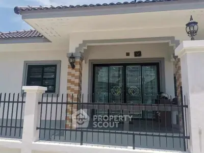 Charming single-story home with decorative front gate and modern exterior lighting.