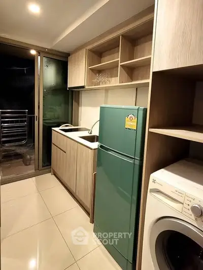 Modern kitchen with green fridge and washing machine in sleek apartment