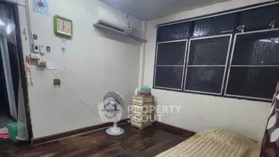 Cozy bedroom with air conditioning and wooden flooring, featuring a fan and ample natural light from large windows.