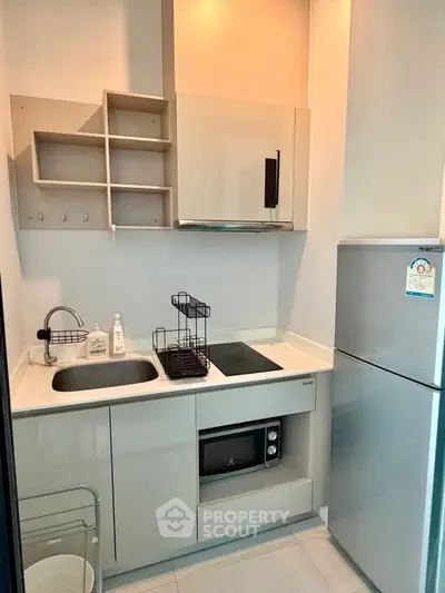 Modern compact kitchen with sleek cabinetry and built-in appliances in a stylish apartment.