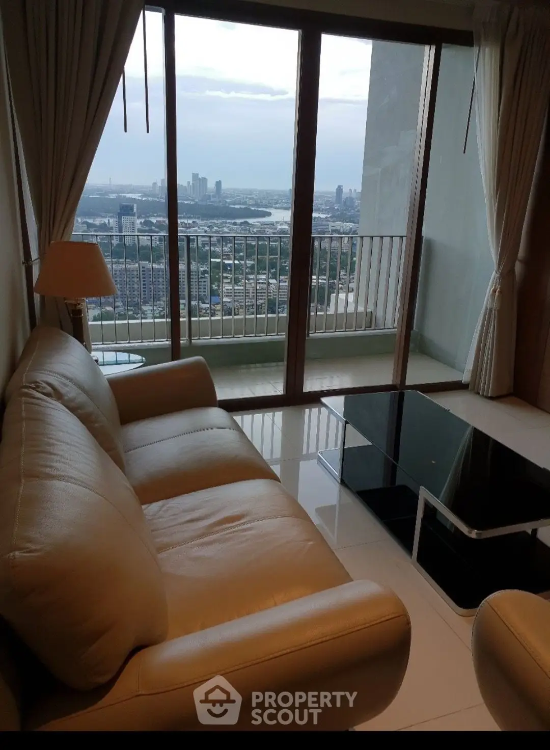 Luxurious living room with stunning city view from high-rise apartment balcony.