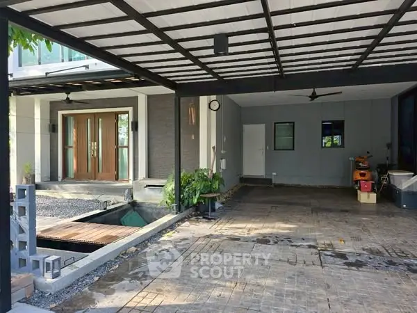 Spacious modern home entrance with covered parking and stylish wooden doors.