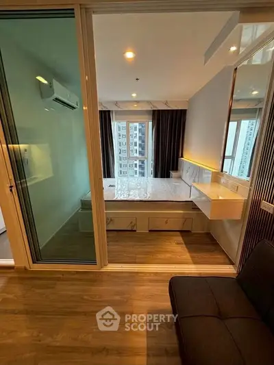 Modern bedroom with large windows and wooden flooring in a high-rise apartment.