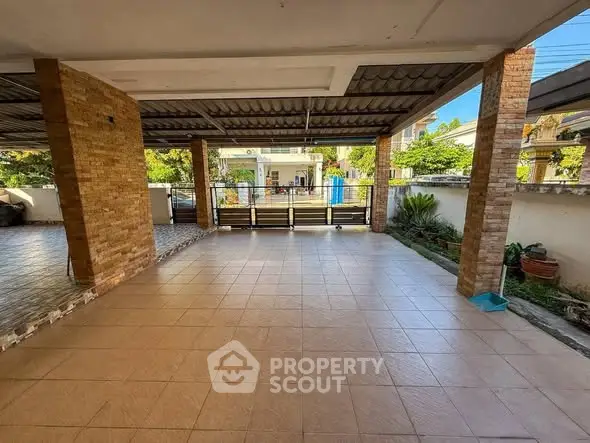 Spacious covered parking area with tiled flooring and brick columns in a residential property.