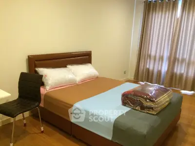 Cozy bedroom with modern furnishings and ample natural light from large window.